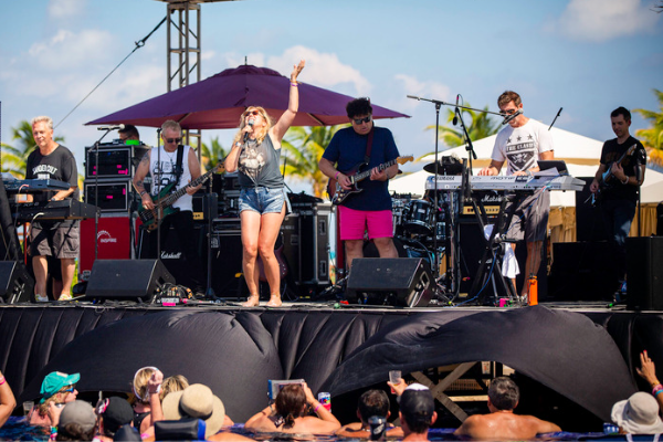 Gen X woman singing rock and roll for the crowd on the pool stage.
