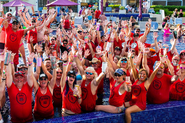 Large group of happy adults wearing group themed t-shirts in the pool.
